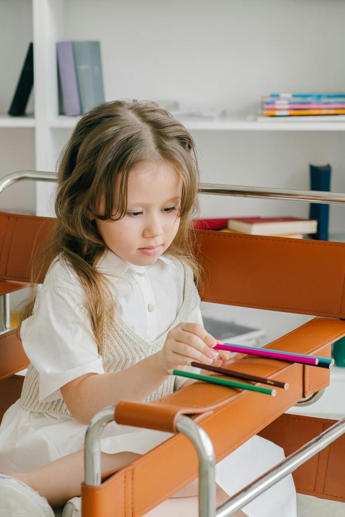 Girl lining up pencils on chair